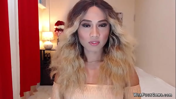 Asain blonde TS wanks cock in chair in front of webcam
